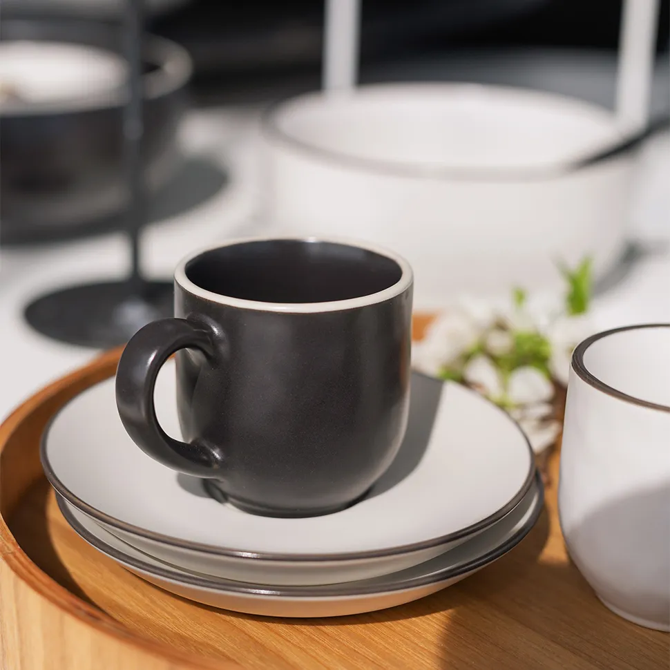 Tasse noire sur des soucoupes blanches sur un plateau en bois